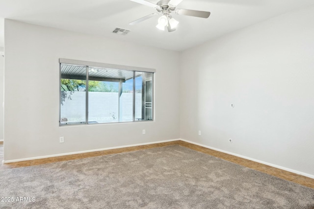 carpeted empty room with baseboards, visible vents, and a ceiling fan