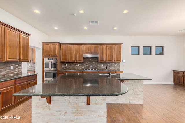 5713 W Rowel Rd, Phoenix, AZ 85083 - kitchen featuring appliances with stainless steel finishes, sink, a kitchen breakfast bar, dark stone counters, and a kitchen island with sink