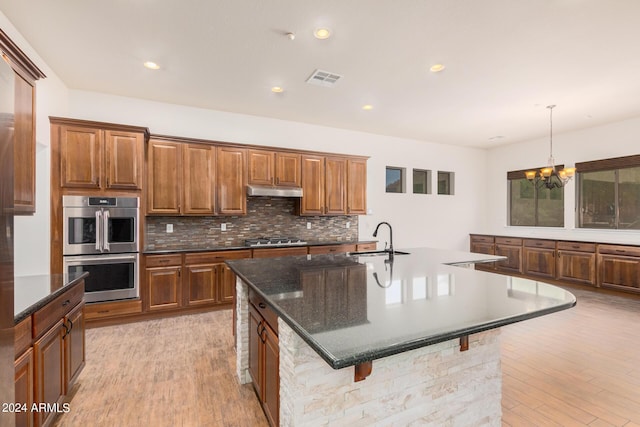 5713 W Rowel Rd, Phoenix, AZ 85083 - kitchen featuring sink, a kitchen bar, hanging light fixtures, a kitchen island with sink, and stainless steel appliances