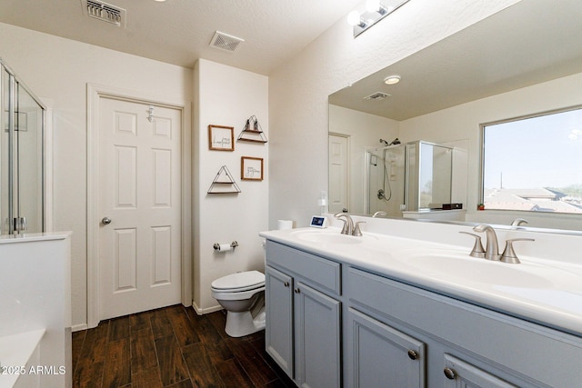 bathroom featuring a shower with door, toilet, and vanity