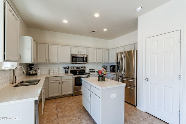 kitchen with light tile patterned floors, appliances with stainless steel finishes, backsplash, a kitchen island, and sink