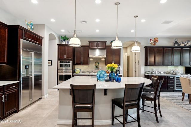 kitchen with pendant lighting, a center island with sink, dark brown cabinetry, and appliances with stainless steel finishes