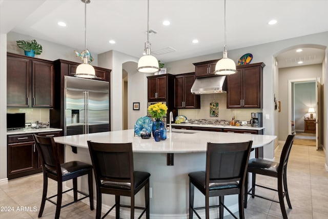 kitchen featuring appliances with stainless steel finishes, an island with sink, sink, a kitchen bar, and hanging light fixtures