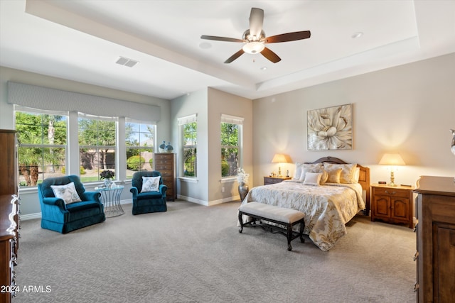 carpeted bedroom with ceiling fan and a tray ceiling