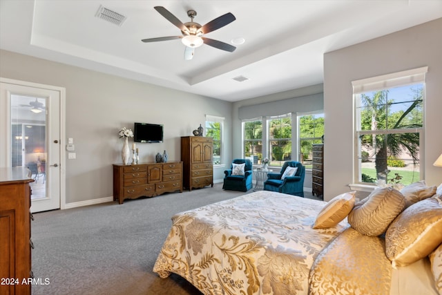 carpeted bedroom with a raised ceiling and ceiling fan