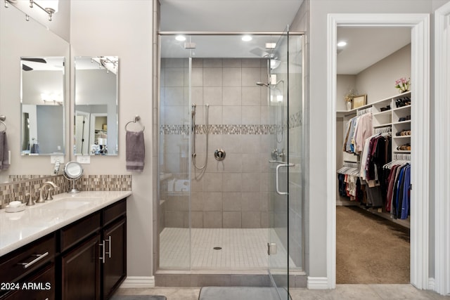 bathroom with a shower with door, vanity, and tile patterned floors