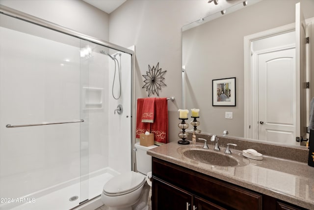 bathroom featuring vanity, a shower with door, and toilet