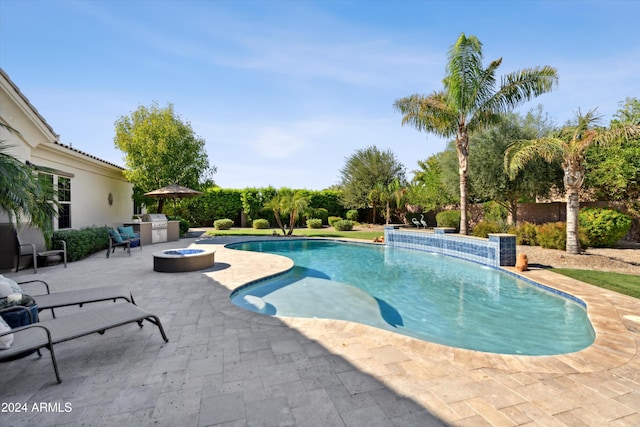 view of pool with exterior kitchen, a patio, pool water feature, and a fire pit