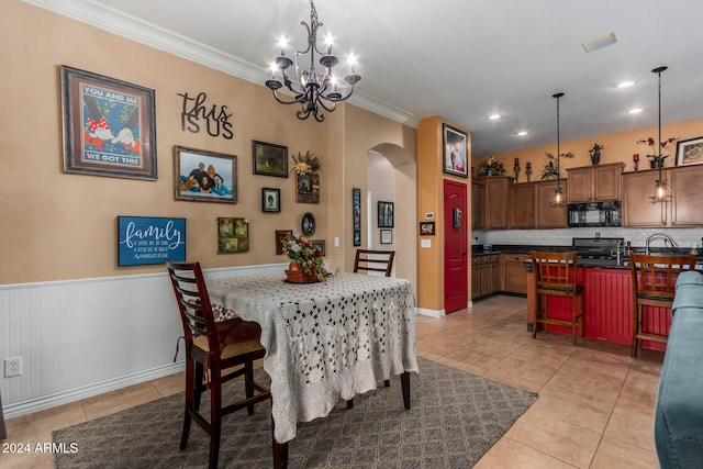 dining area with a chandelier, crown molding, and light tile patterned floors