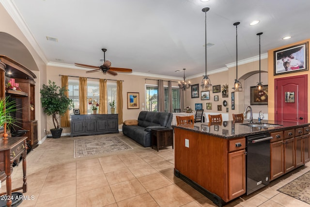 kitchen featuring dark stone counters, crown molding, sink, pendant lighting, and a center island with sink