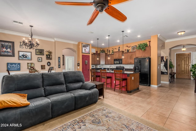 living room featuring ceiling fan with notable chandelier, sink, crown molding, and light tile patterned flooring