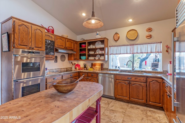 kitchen featuring lofted ceiling, sink, butcher block counters, hanging light fixtures, and stainless steel appliances