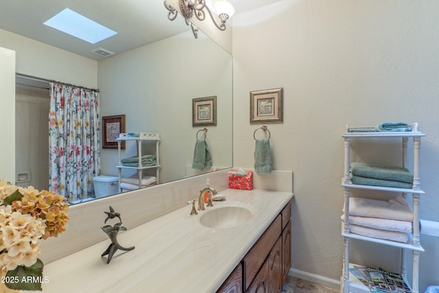 bathroom with vanity, toilet, and a skylight