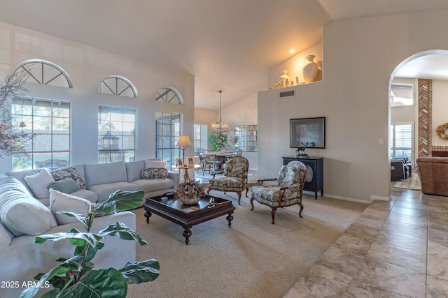 living room with a towering ceiling, a healthy amount of sunlight, and a notable chandelier