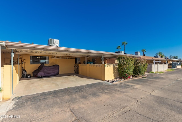 711 E Laurel Dr Unit 17, Casa Grande, AZ 85122 - exterior space featuring an attached carport, fence, aphalt driveway, central AC, and concrete block siding