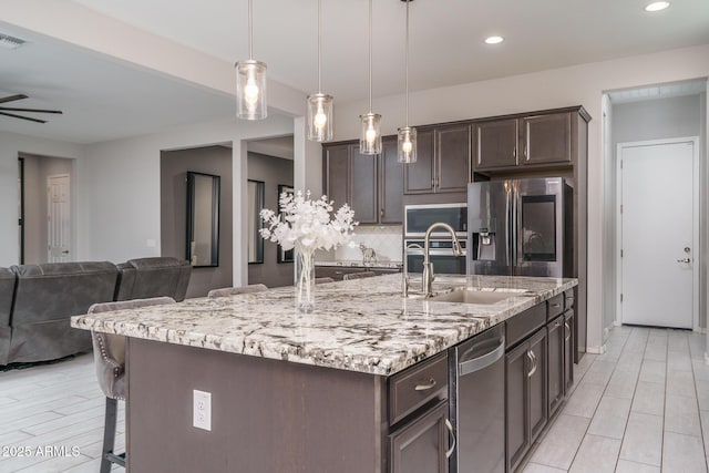 kitchen with pendant lighting, sink, a kitchen breakfast bar, a large island, and stainless steel appliances