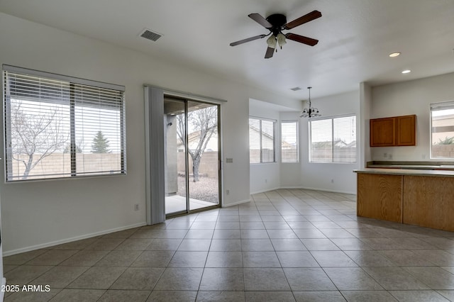 unfurnished living room with visible vents, ceiling fan with notable chandelier, recessed lighting, light tile patterned floors, and baseboards