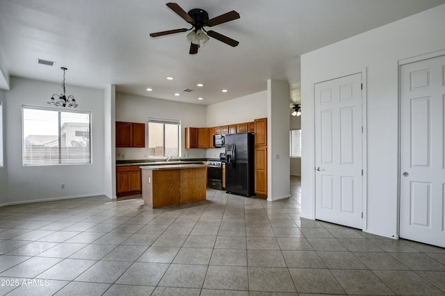 kitchen with light tile patterned floors, a kitchen island, black appliances, and ceiling fan with notable chandelier