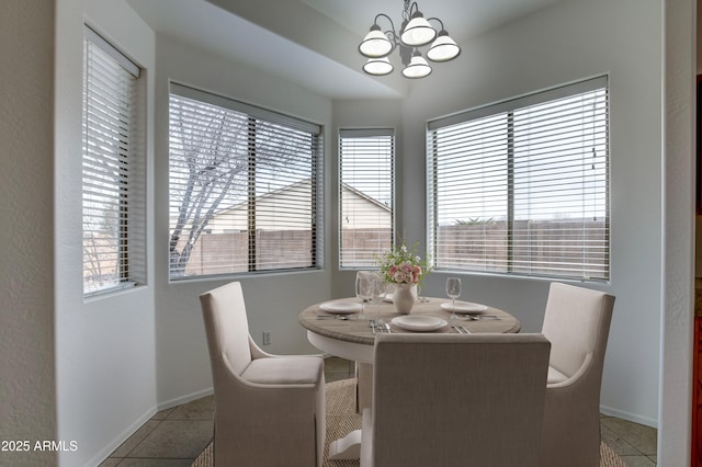 dining space featuring tile patterned floors, baseboards, and a chandelier