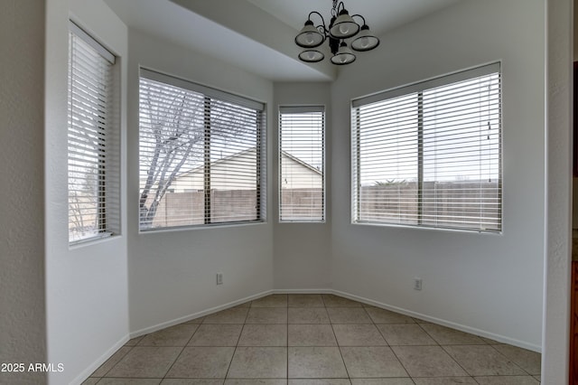 spare room featuring light tile patterned floors, baseboards, and a chandelier