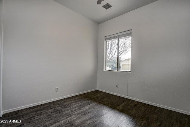 empty room featuring visible vents, dark wood-type flooring, baseboards, lofted ceiling, and a ceiling fan