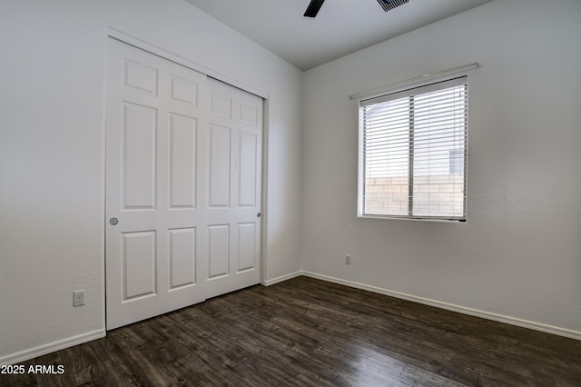 unfurnished bedroom featuring visible vents, ceiling fan, baseboards, a closet, and dark wood-style floors