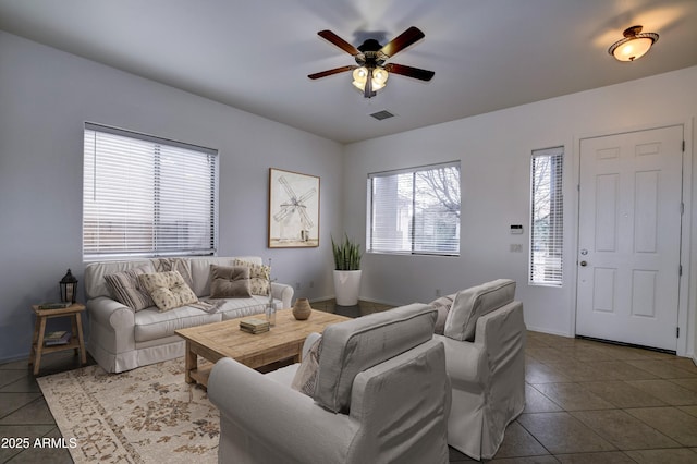 tiled living room with visible vents, baseboards, and a ceiling fan