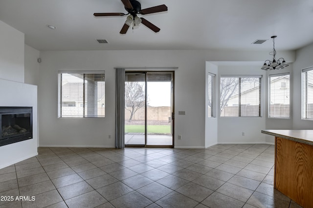 unfurnished living room with visible vents, baseboards, a glass covered fireplace, and tile patterned flooring