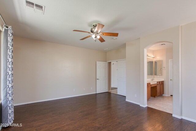 7421 S 25th Ln, Phoenix, AZ 85041 - unfurnished bedroom featuring arched walkways, wood finished floors, baseboards, ensuite bathroom, and a ceiling fan