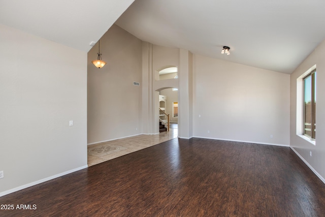 7421 S 25th Ln, Phoenix, AZ 85041 - unfurnished room featuring arched walkways, wood finished floors, high vaulted ceiling, stairway, and baseboards