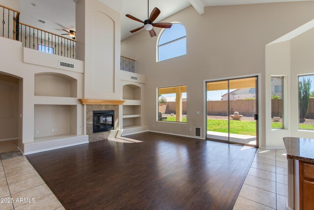 7421 S 25th Ln, Phoenix, AZ 85041 - unfurnished living room featuring a ceiling fan, built in shelves, high vaulted ceiling, a tiled fireplace, and baseboards