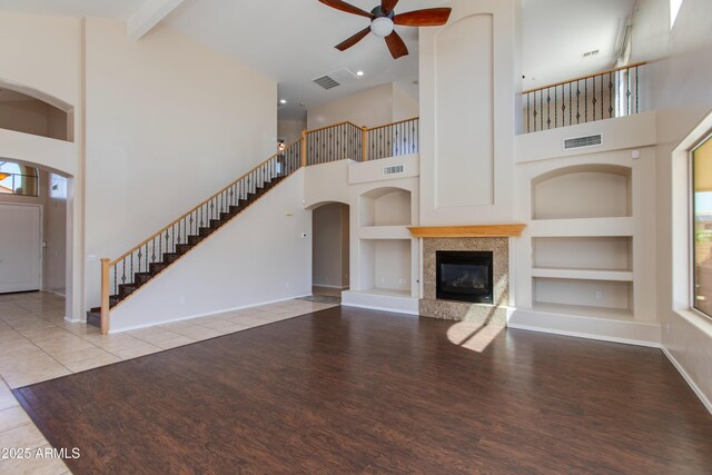 7421 S 25th Ln, Phoenix, AZ 85041 - unfurnished living room with a high ceiling, built in shelves, ceiling fan, wood finished floors, and stairway