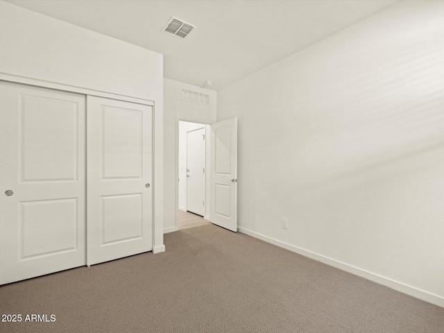 unfurnished bedroom with light carpet and a closet