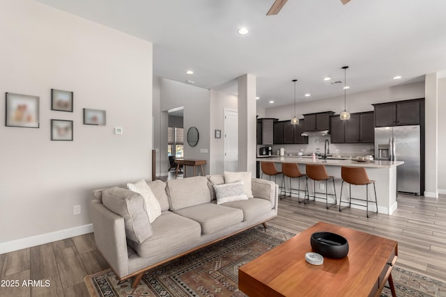 living room with light wood-style floors, baseboards, and recessed lighting