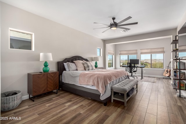 bedroom with a ceiling fan, visible vents, baseboards, and wood finished floors