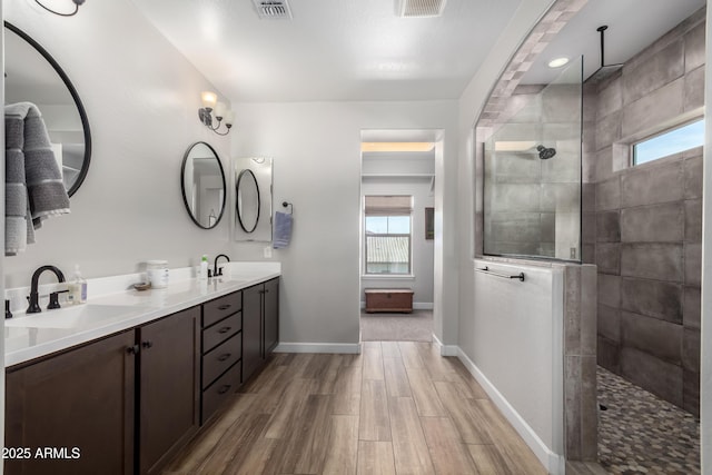 bathroom featuring baseboards, visible vents, a walk in shower, and a sink