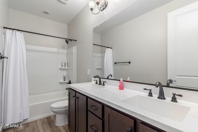 bathroom with toilet, double vanity, a sink, and wood finished floors