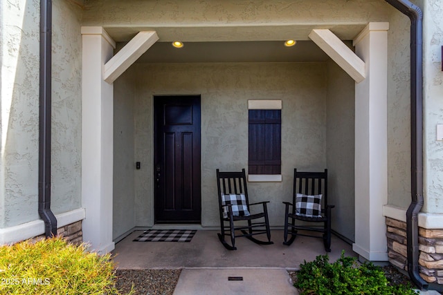 property entrance featuring a porch and stucco siding