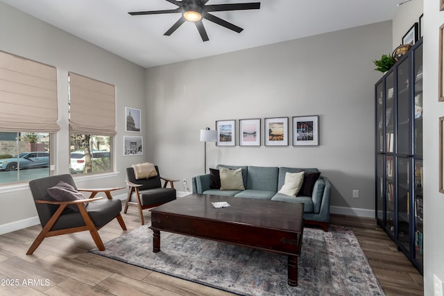 living room with a ceiling fan, baseboards, and wood finished floors