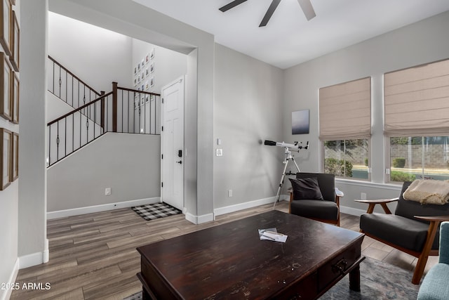 living area featuring ceiling fan, stairs, baseboards, and wood finished floors