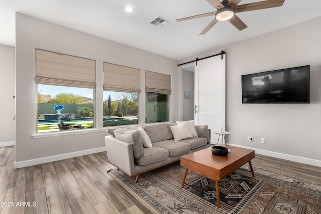 living area featuring a barn door, baseboards, and wood finished floors