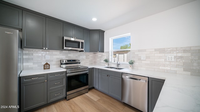 kitchen with gray cabinets, sink, light wood-type flooring, and appliances with stainless steel finishes