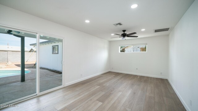 spare room with light wood-type flooring, a wealth of natural light, and ceiling fan