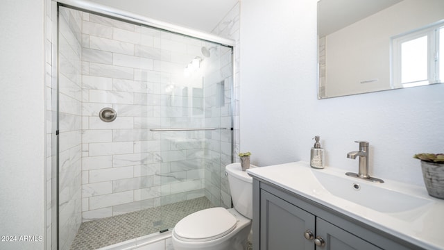 bathroom featuring vanity, a shower with shower door, and toilet