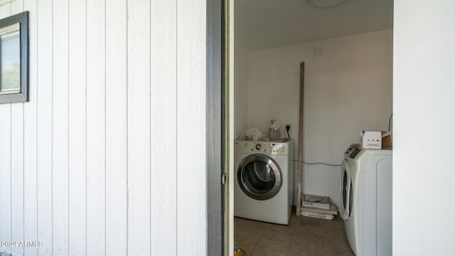 washroom with washing machine and dryer and wood walls