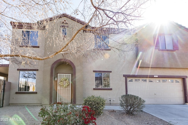 view of front of house featuring a garage, concrete driveway, and stucco siding