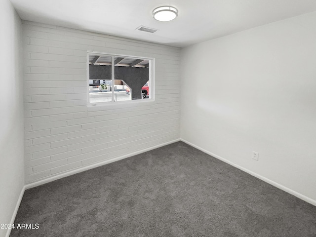 spare room with dark carpet, visible vents, and baseboards