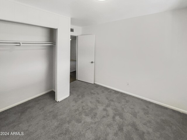 unfurnished bedroom featuring baseboards, carpet floors, and a closet