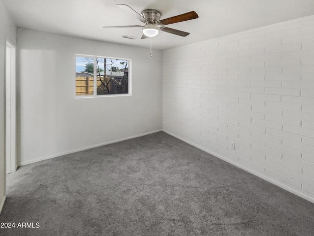 spare room with visible vents, baseboards, carpet, brick wall, and a ceiling fan