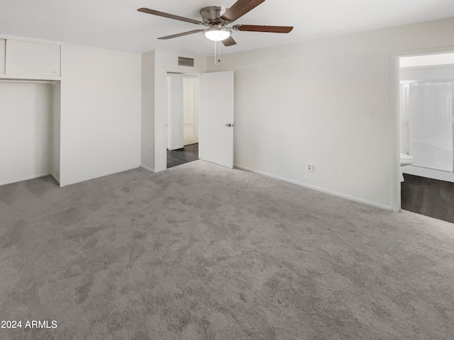 unfurnished bedroom with carpet, a closet, ensuite bathroom, and ceiling fan